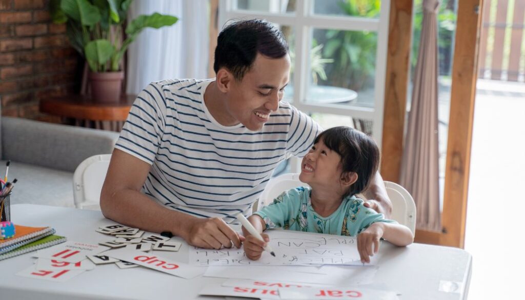 Father teaching daughter to read using phonics