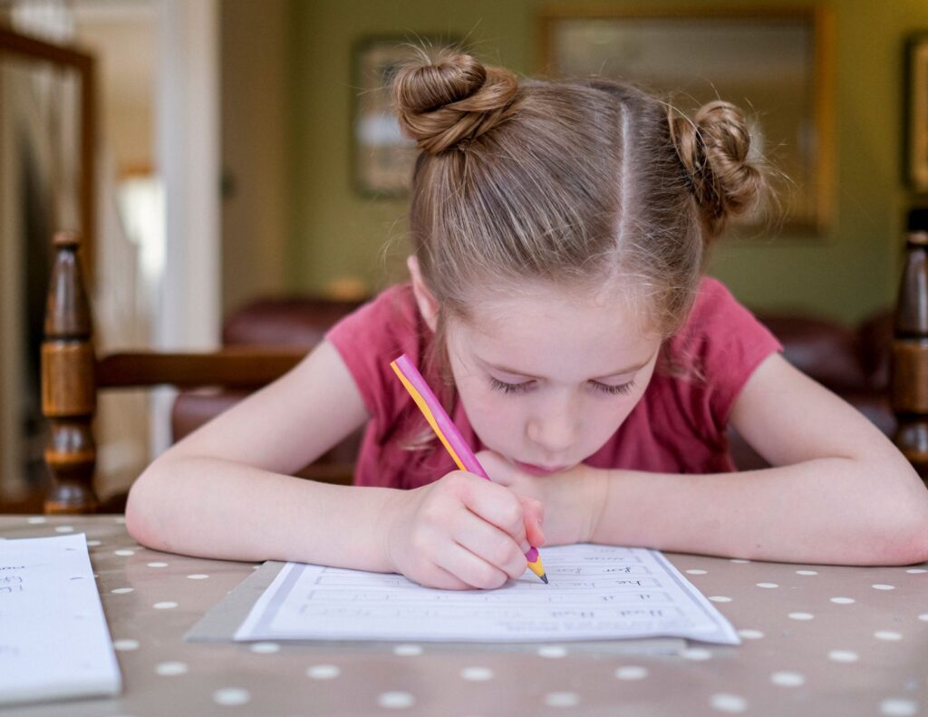 Young girl concentrating intently on her cursive writing practice book